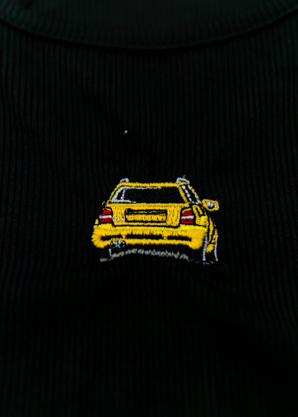 A black Audi crop top for women. Photo is a close up view of the top with an embroidered imola yellow Audi B5 RS4. Fabric composition is polyester, and elastine. The material is stretchy, ribbed, and non-transparent. The style of this shirt is sleeveless, with a crewneck neckline.