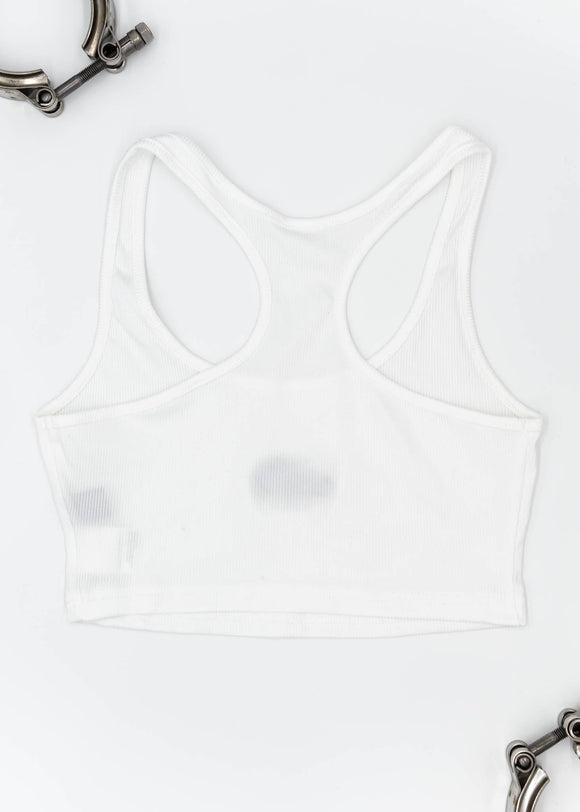 A white Audi crop top for women. Photo is a back view of the top with an embroidered Nogaro Blue Audi 80 RS2 Avant made by Porsche. Fabric composition is polyester, and cotton. The material is stretchy, ribbed, and non-transparent. The style of this shirt is sleeveless, with a scoop neckline.