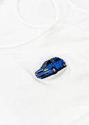 A white Audi crop top for women. Photo is a close up view of the top with an embroidered Nogaro Blue Audi 80 RS2 Avant made by Porsche. Fabric composition is polyester, and cotton. The material is stretchy, ribbed, and non-transparent. The style of this shirt is sleeveless, with a scoop neckline.