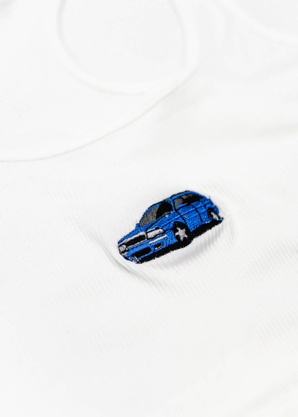 A white Audi crop top for women. Photo is a close up view of the top with an embroidered Nogaro Blue Audi 80 RS2 Avant made by Porsche. Fabric composition is polyester, and cotton. The material is stretchy, ribbed, and non-transparent. The style of this shirt is sleeveless, with a scoop neckline.