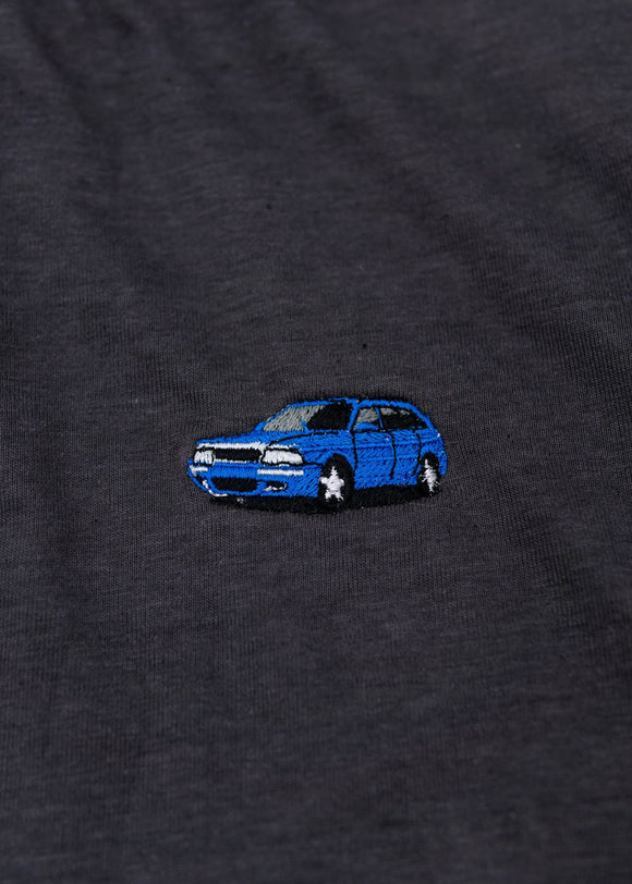 A dark grey cropped t-shirt for Audi women. Close up view of a 100% cotton crop tee with an embroidered Nogaro Blue Audi 80 RS2 Avant made by Porsche. The material is stretchy, and non-transparent with a crewneck neckline and short sleeves.