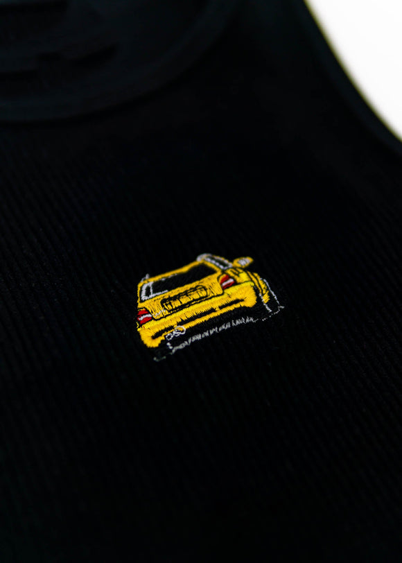 A black Audi crop top for women. Photo is a close up view of the top with an embroidered imola yellow Audi B5 RS4. Fabric composition is polyester, and elastine. The material is stretchy, ribbed, and non-transparent. The style of this shirt is sleeveless, with a crewneck neckline.