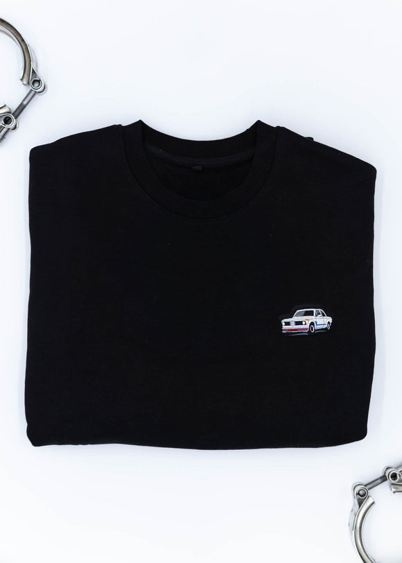 A black BMW crewneck sweater for men. Photo is a close up of the sweater with an embroidered BMW 2002 Turbo. Fabric is composed of high quality 80% cotton, and 20% polyester and fits to size. The style is long sleeve, crew neck, and embroidery on left chest.