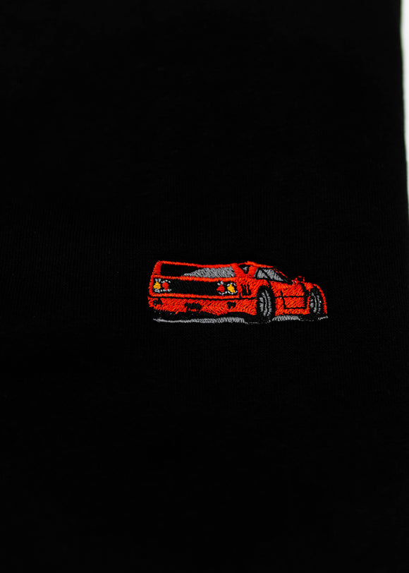 Close up of an embroidered F40 on a black men's high quality crewneck sweater. Photo shows the high quality detailed embroidery of a red F40. Fabric composition of the shirt is cotton and polyester. The material is very soft, stretchy, and non-transparent. The style of this sweater is a crewneck, long sleeve, elastic bottom, with embroidery on the left chest.