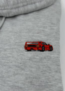 Close up of an embroidered F40 on a women's high quality cropped grey hoodie. Photo shows the detailed embroidery of a red F40. Fabric composition of this cropped sweater is polyester and cotton. The material is very soft, stretchy, and non-transparent. The style of this crop hoodie is a crewneck, drawstring hoodie, hooded, long sleeve, cropped, with embroidery on the left chest.