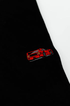 Close up of an embroidered F40 on a black men's cotton t-shirt. Photo shows the high quality detailed embroidery of a red F40. Fabric composition of the shirt is polyester and cotton. The material is very soft, stretchy, and non-transparent. The style of this t-shirt is short sleeve, round bottom, crewneck, with embroidery on the left chest.