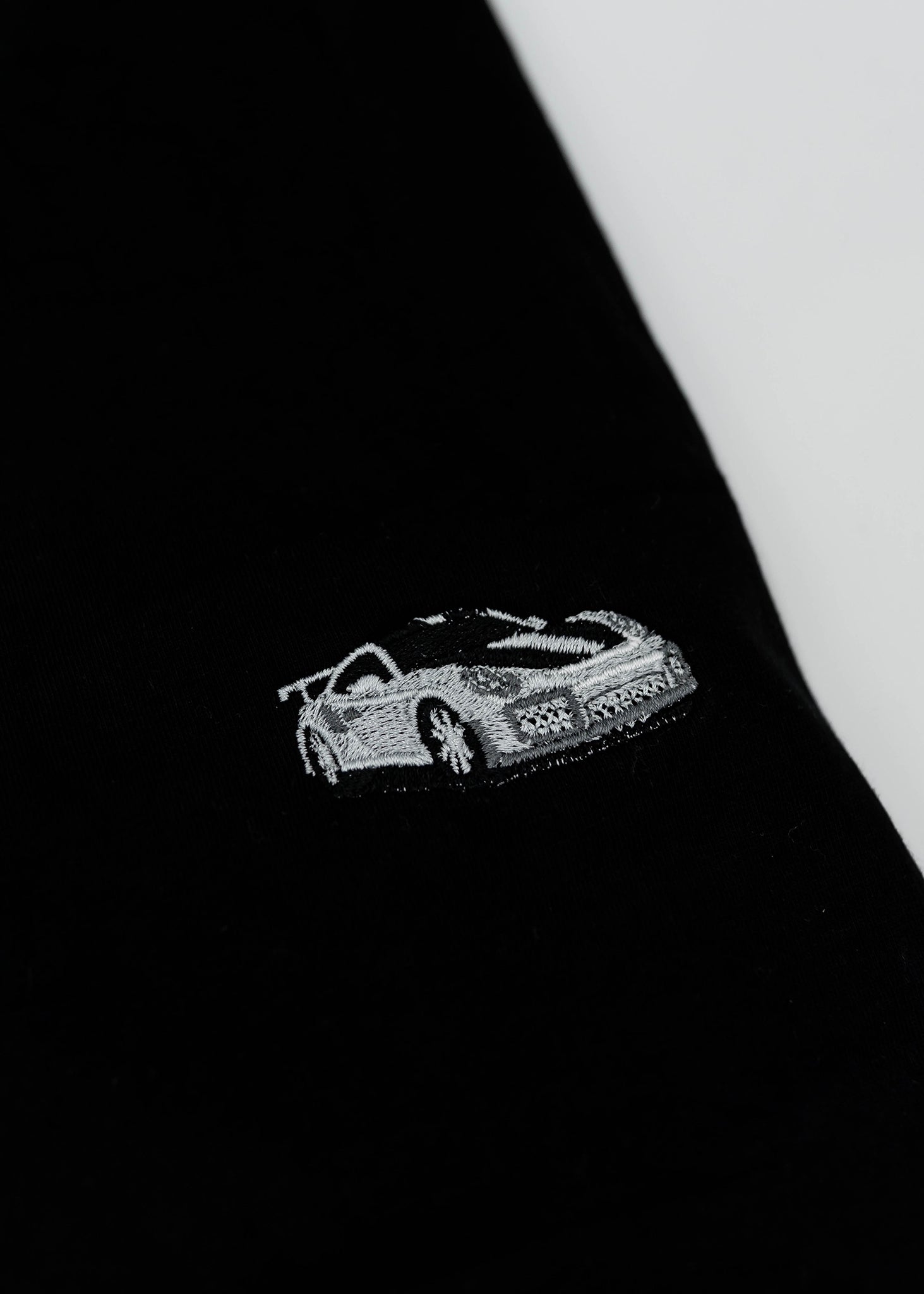 Close up of an embroidered 991.2 GT2 RS on a women's high quality cropped t-shirt. Photo shows the detailed embroidery of a white, silver, and carbon fiber GT2 RS. Fabric composition of this tee is 100% cotton. The material is very soft, stretchy, and non-transparent. The style of this tshirt is a crewneck, short sleeve, cropped at the waist, with embroidery on the left chest.