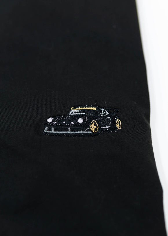 A Black RWB Porsche 930 911 Turbo T-Shirt for men. Photo is a close up view of the shirt with Akira Nakai's RWB Porsche 930 911 Turbo Stella Artois. Fabric composition is a polyester, and cotton mix. The material is very stretchy, soft, comfortable, and non-transparent. The style of this shirt is short sleeve, with a crewneck neckline.