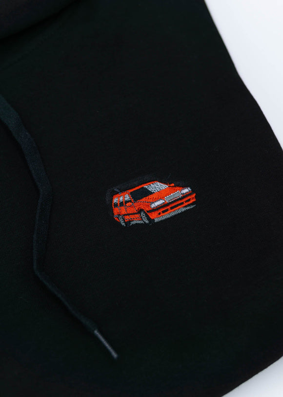 A black Volvo unisex hoodie for men and women. Photo is a close up view of the sweater with an embroidered Volvo 850R. Fabric composition is cotton, polyester, and rayon. The material is very soft, stretchy, and non-transparent. The style of this hoodie is long sleeve, crewneck with a hood, hooded, with embroidery on the left chest.