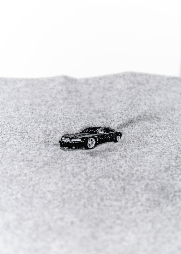 A grey Audi crop top for women. Photo is a close up view of the shirt with an embroidered Black Audi D2 S8. Fabric composition is 100% polyester. The material is very soft, comfortable, non-transparent. The style of this shirt is sleeveless, spaghetti straps, with a straight neckline.