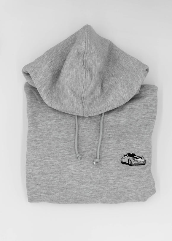 Close up of an embroidered 991.2 GT2 RS on a women's high quality cropped grey hoodie. Photo shows the detailed embroidery of a white, silver, and carbon fiber GT2 RS. Fabric composition of this cropped sweater is polyester and cotton. The material is very soft, stretchy, and non-transparent. The style of this crop hoodie is a crewneck, drawstring hoodie, hooded, long sleeve, cropped, with embroidery on the left chest.