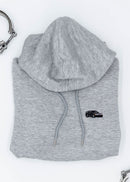A grey Mercedes-Benz cropped hoodie for women. Photo is a close up view of the cropped sweater with an embroidered W201 190E 2.5-16 Evo II. Fabric composition is 100% cotton. The material is soft, comfortable, breathable, and non-transparent. The style of this crop hoodie is long sleeve, crewneck with a hood, hooded, with embroidery on the chest.