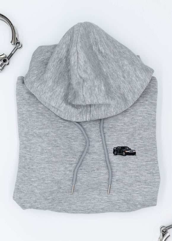 A grey Mercedes-Benz cropped hoodie for women. Photo is a close up view of the cropped sweater with an embroidered W201 190E 2.5-16 Evo II. Fabric composition is 100% cotton. The material is soft, comfortable, breathable, and non-transparent. The style of this crop hoodie is long sleeve, crewneck with a hood, hooded, with embroidery on the chest.