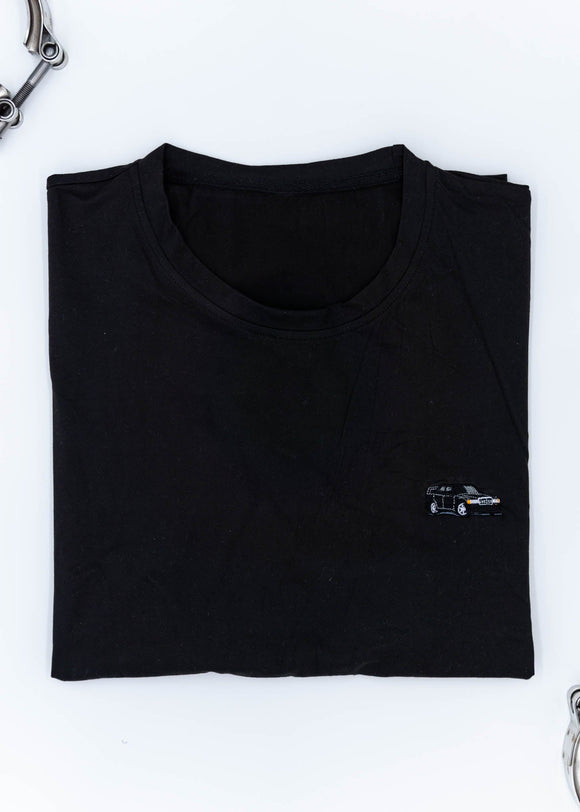 A black Mercedes-Benz t-shirt for men. Photo is a close up of the shirt with an embroidered black W201 190E Evo II. Fabric composition is a polyester. The material is very soft, stretchy, non-transparent. The style of this shirt is short sleeve, with a crewneck neckline.