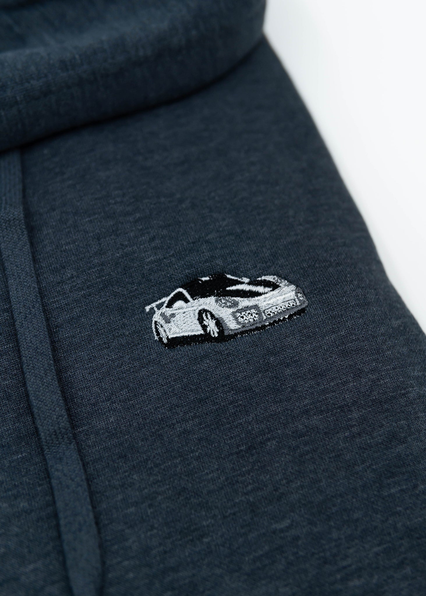 Close up of an embroidered GT2 RS on a navy blue unisex hoodie for men and women. Photo shows the high quality detailed embroidery of a white, silver, carbon fiber GT2 RS on the left chest. Fabric composition of the sweater is cotton, polyester, and rayon. The material is very soft, stretchy, and non-transparent. The style of this hoodie is long sleeve, crewneck with a hood, hooded, with embroidery on the left chest.