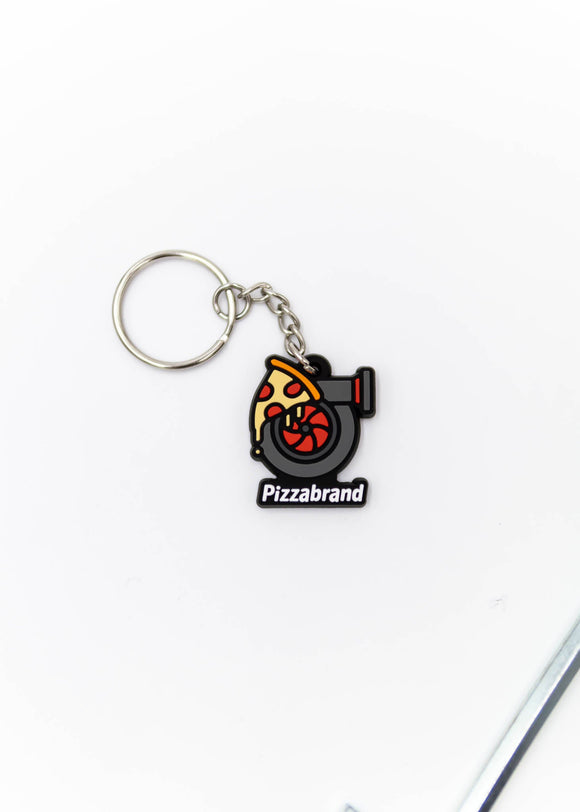 A pizzabrand pizza and turbo keychain. Made of rubber and stainless steel. Photo is of a close up of the pizza melting on a turbo with the brand name.