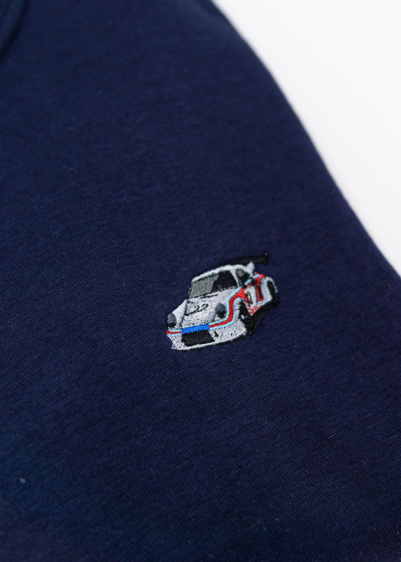 A navy blue Porsche race car crewneck sweater for men. Photo is a close up of the sweater with an embroidered Martini R13 Porsche 911 Carrera RSR 2.1 Turbo . Fabric is 100% cotton and high quality and fits to size. The style is long sleeve, crew neck, and embroidery on left chest.