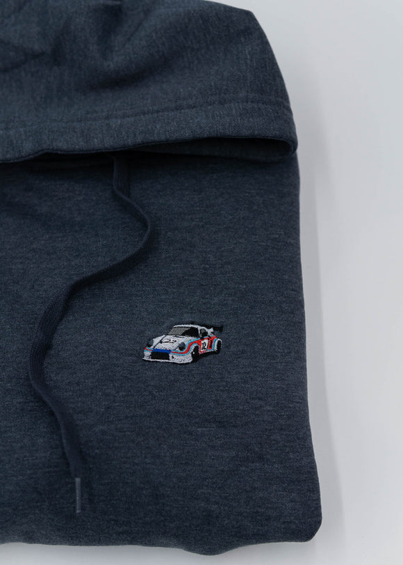 A dark grey Porsche racing unisex hoodie for men and women. Photo is a close up of the sweater with an embroidered Martini R13 Porsche 911 Carrera RSR 2.1 Turbo. Fabric composition is cotton, polyester, and rayon. The material is very soft, stretchy, and non-transparent. The style of this hoodie is long sleeve, crewneck with a hood, hooded, with embroidery on the left chest.