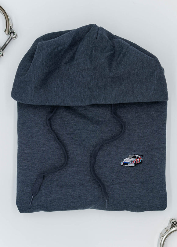 A dark grey Porsche racing unisex hoodie for men and women. Photo is a close up of the sweater with an embroidered Martini R13 Porsche 911 Carrera RSR 2.1 Turbo. Fabric composition is cotton, polyester, and rayon. The material is very soft, stretchy, and non-transparent. The style of this hoodie is long sleeve, crewneck with a hood, hooded, with embroidery on the left chest.