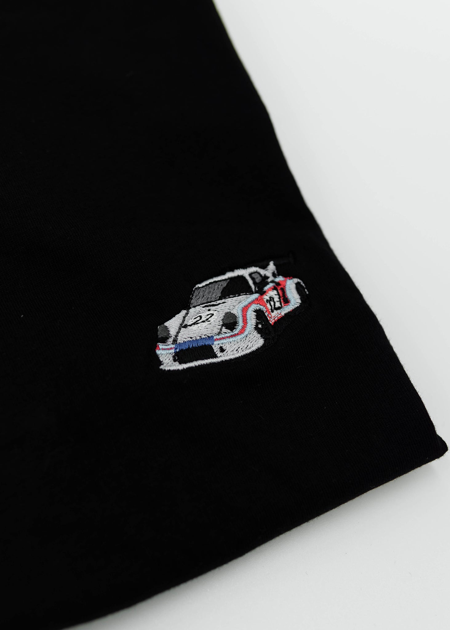 Close up of an embroidered R13 1974 911 RSR Turbo on a women's high quality cropped t-shirt. Photo shows the detailed embroidery of a R13 1974 911 RSR Turbo. Fabric composition of this tee is 100% cotton. The material is very soft, stretchy, and non-transparent. The style of this tshirt is a crewneck, short sleeve, cropped at the waist, with embroidery on the left chest.