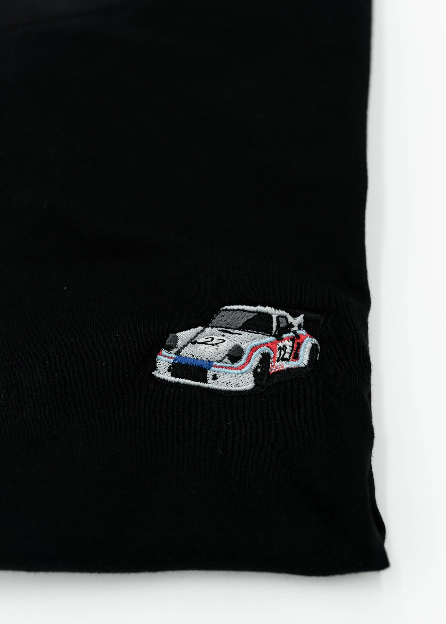 Close up of an embroidered R13 1974 911 RSR Turbo on a women's high quality cropped t-shirt. Photo shows the detailed embroidery of a R13 1974 911 RSR Turbo. Fabric composition of this tee is 100% cotton. The material is very soft, stretchy, and non-transparent. The style of this tshirt is a crewneck, short sleeve, cropped at the waist, with embroidery on the left chest.