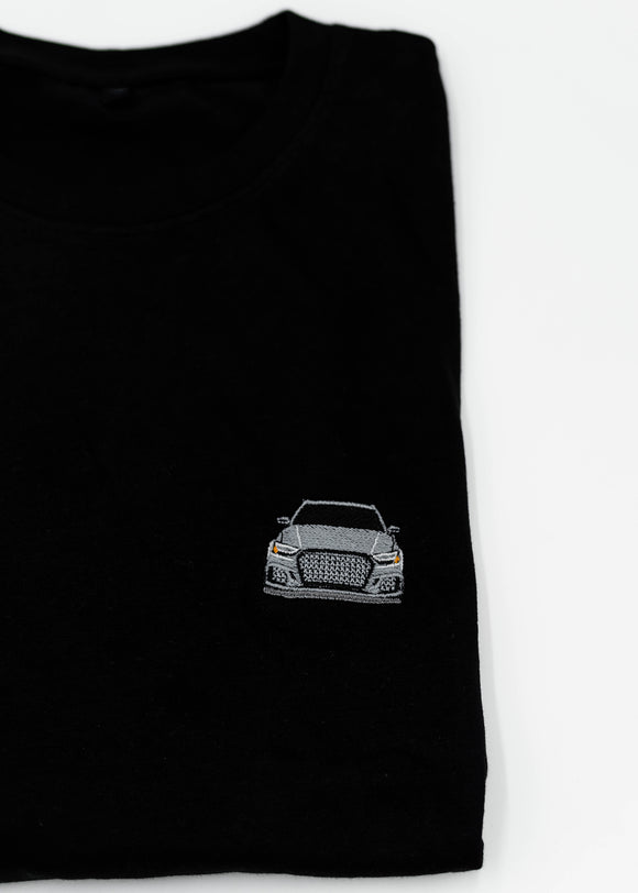 Close up of an embroidered 8V RS3 on a black men's cotton t-shirt. Photo shows the high quality detailed embroidery of a nardo grey 8V RS3. Fabric composition of the shirt is polyester and cotton. The material is very soft, stretchy, and non-transparent. The style of this t-shirt is short sleeve, round bottom, crewneck, with embroidery on the left chest.