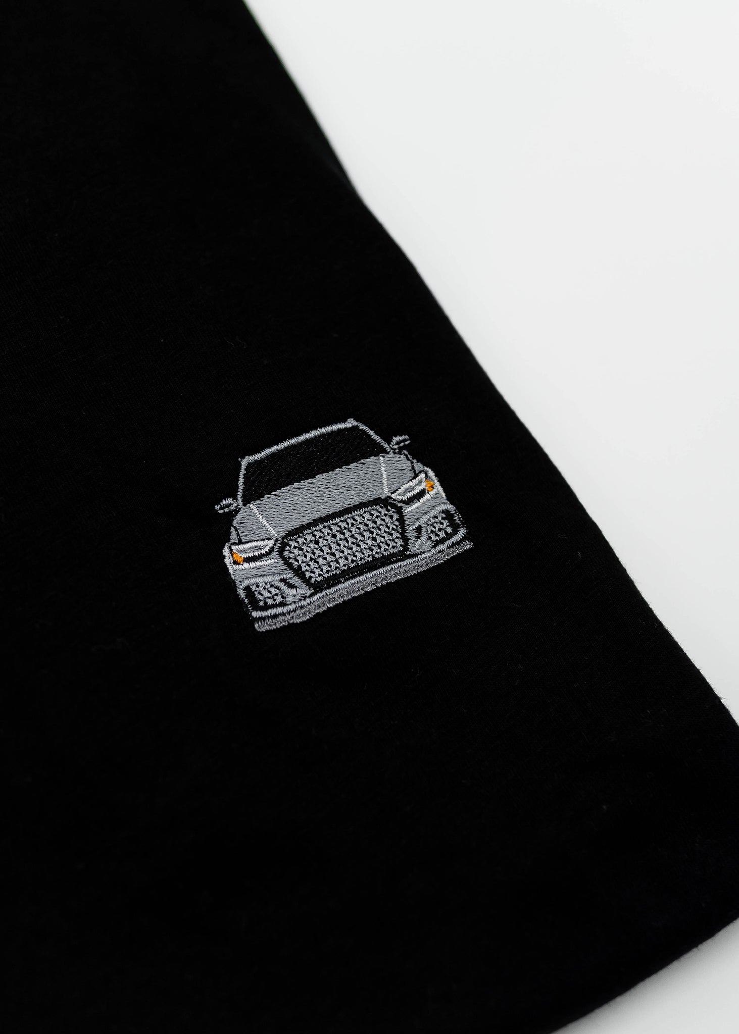 Close up of an embroidered 8V RS3 on a black men's cotton t-shirt. Photo shows the high quality detailed embroidery of a nardo grey 8V RS3. Fabric composition of the shirt is polyester and cotton. The material is very soft, stretchy, and non-transparent. The style of this t-shirt is short sleeve, round bottom, crewneck, with embroidery on the left chest.