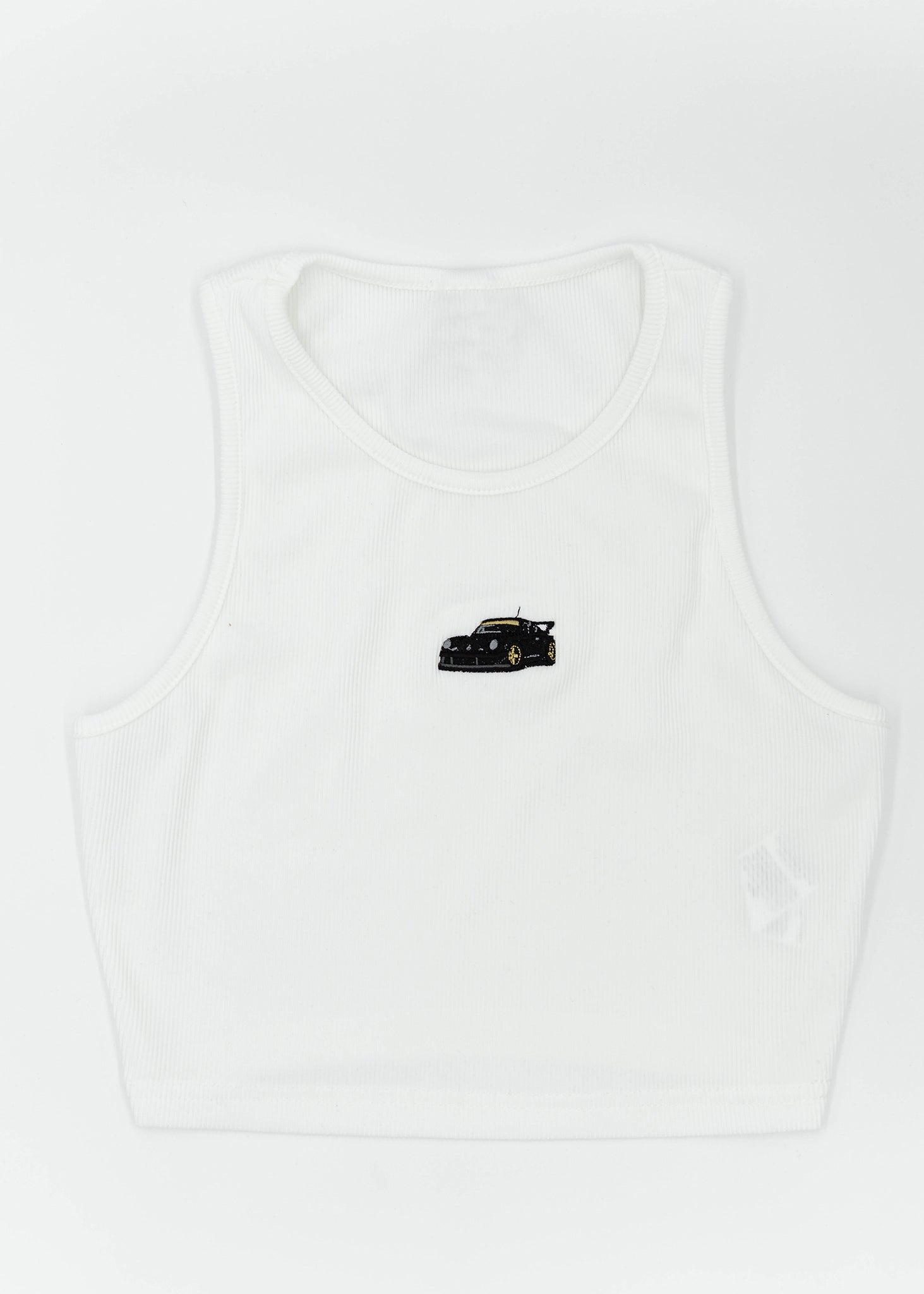 A white ribbed stretchy crop top with embroidery of a small RWB 930 911 Turbo - Akira Nakai "Stella Artois" on the front. Full size front view of the white shirt with an embroidered RWB 930 911 Turbo. Fabric composition of this top is 95% polyester, and 5% elastane. The material is very stretchy, and form fitting. The style of this shirt is scoop neck, sleeveless, cropped at the waist, with embroidery in the middle.