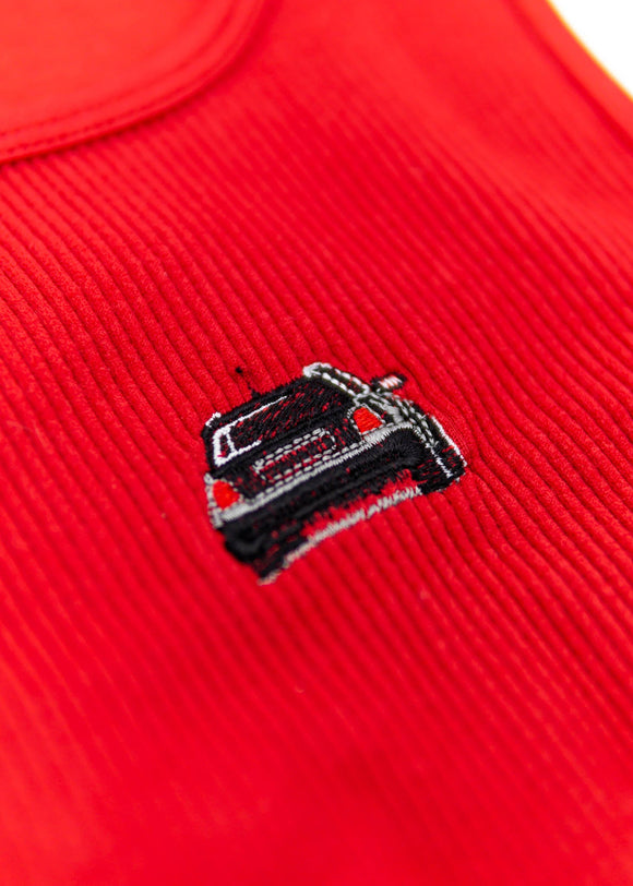 A red Audi crop top for women. Photo is a close up view of the top with an embroidered black Audi B5 RS4. Fabric composition is polyester, and elastine. The material is stretchy, ribbed, and non-transparent. The style of this shirt is sleeveless, with a crewneck neckline.