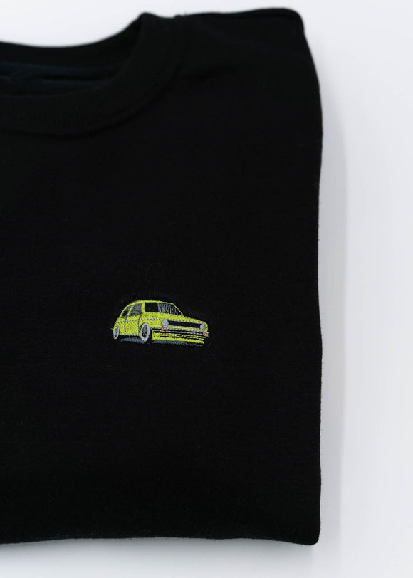 A black VW Volkswagen crewneck sweater for men. Photo is a close up of the sweater with an embroidered modified green VW Mk1 Golf. Fabric is 100% cotton and high quality and fits to size. The style is long sleeve, crew neck, and embroidery on left chest.