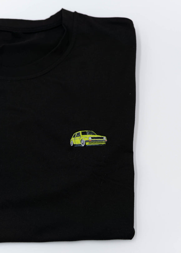 A black VW VolkswagenT-Shirt for men. Photo is a close up of the shirt with an embroidered modified green Mk1 Golf. Fabric composition is 100% polyester. The material is very stretchy, soft, comfortable, breathable, and non-transparent. The style of this shirt is short sleeve, with a crewneck neckline.