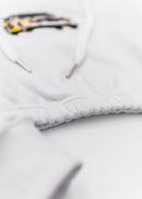 A white Audi cropped hoodie for women. Photo is a front view of the cropped sweater with an embroidered Sport Quattro S1 E2. Fabric composition is cotton, and polyester. The material is soft, stretchy, and non-transparent. The style of this crop hoodie is long sleeve, crewneck with a hood, hooded, with embroidery on the chest.
