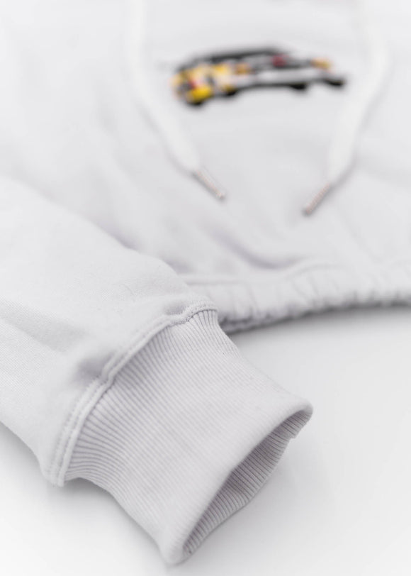 A white Audi cropped hoodie for women. Photo is a front view of the cropped sweater with an embroidered Sport Quattro S1 E2. Fabric composition is cotton, and polyester. The material is soft, stretchy, and non-transparent. The style of this crop hoodie is long sleeve, crewneck with a hood, hooded, with embroidery on the chest.