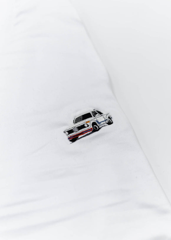 A white BMW 2002 Turbo t-shirt for men. Photo is a close up of the shirt with an embroidered 2002 Turbo. Fabric composition is a polyester and cotton mix. The material is very soft, stretchy, non-transparent. The style of this shirt is short sleeve, with a crewneck neckline.