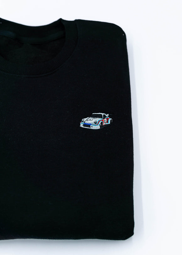 A black 911 RSR 2.1 Turbo crewneck sweater for men. Photo is a close up of the sweater with an embroidered 911 RSR 2.1 Turbo. Fabric is a cotton and polyester mix and high quality and fits to size. The style is long sleeve, crew neck, and embroidery on left chest.