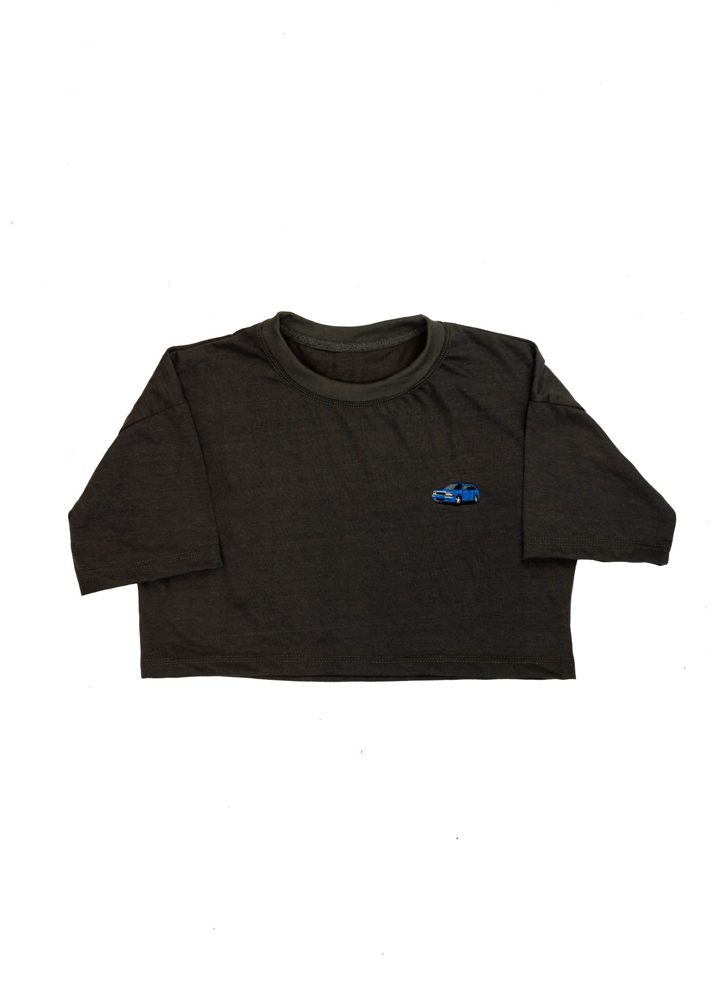 A dark grey cropped t-shirt for Audi women. Front view of a 100% cotton crop tee with an embroidered Nogaro Blue Audi 80 RS2 Avant made by Porsche. The material is stretchy, and non-transparent with a crewneck neckline and short sleeves.