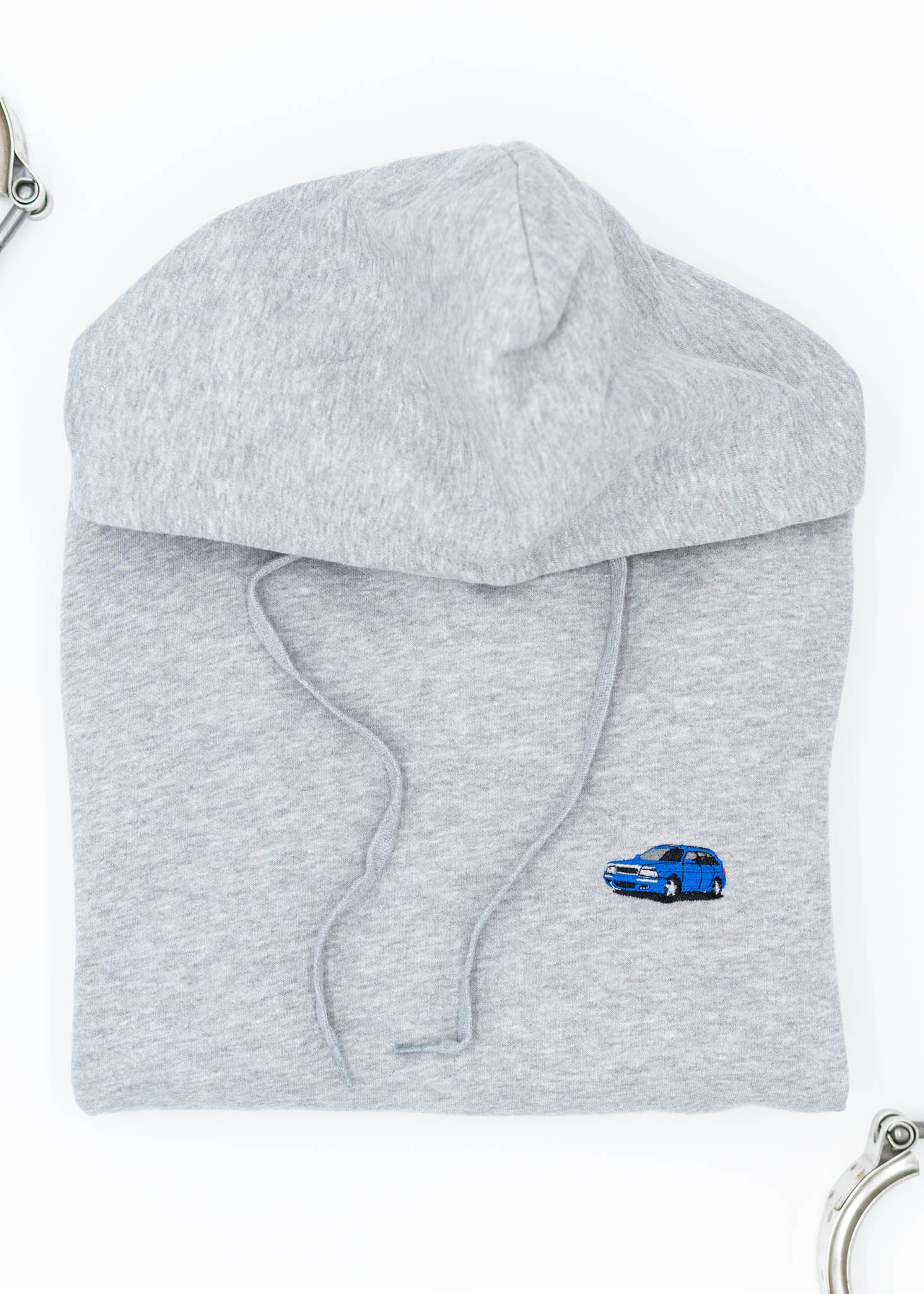 A grey Audi unisex hoodie for men and women. Photo is a front view of the sweater with an embroidered Nogaro Blue Audi 80 RS2 Avant made by Porsche. Fabric composition is cotton, polyester, and rayon. The material is very soft, stretchy, and non-transparent. The style of this hoodie is long sleeve, crewneck with a hood, hooded, with embroidery on the left chest.