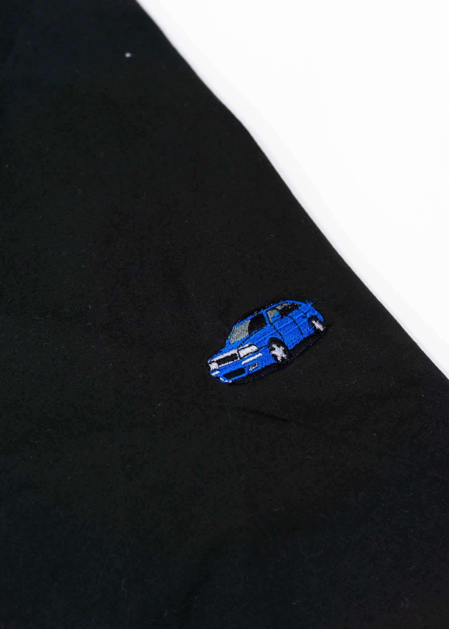 A black Audi t-shirt for men. Photo is a close up of the shirt with an embroidered a Nogaro Blue Audi 80 Avant made by Porsche. Fabric composition is 100% polyester. The material is very soft, stretchy, non-transparent. The style of this shirt is short sleeve, with a crewneck neckline.