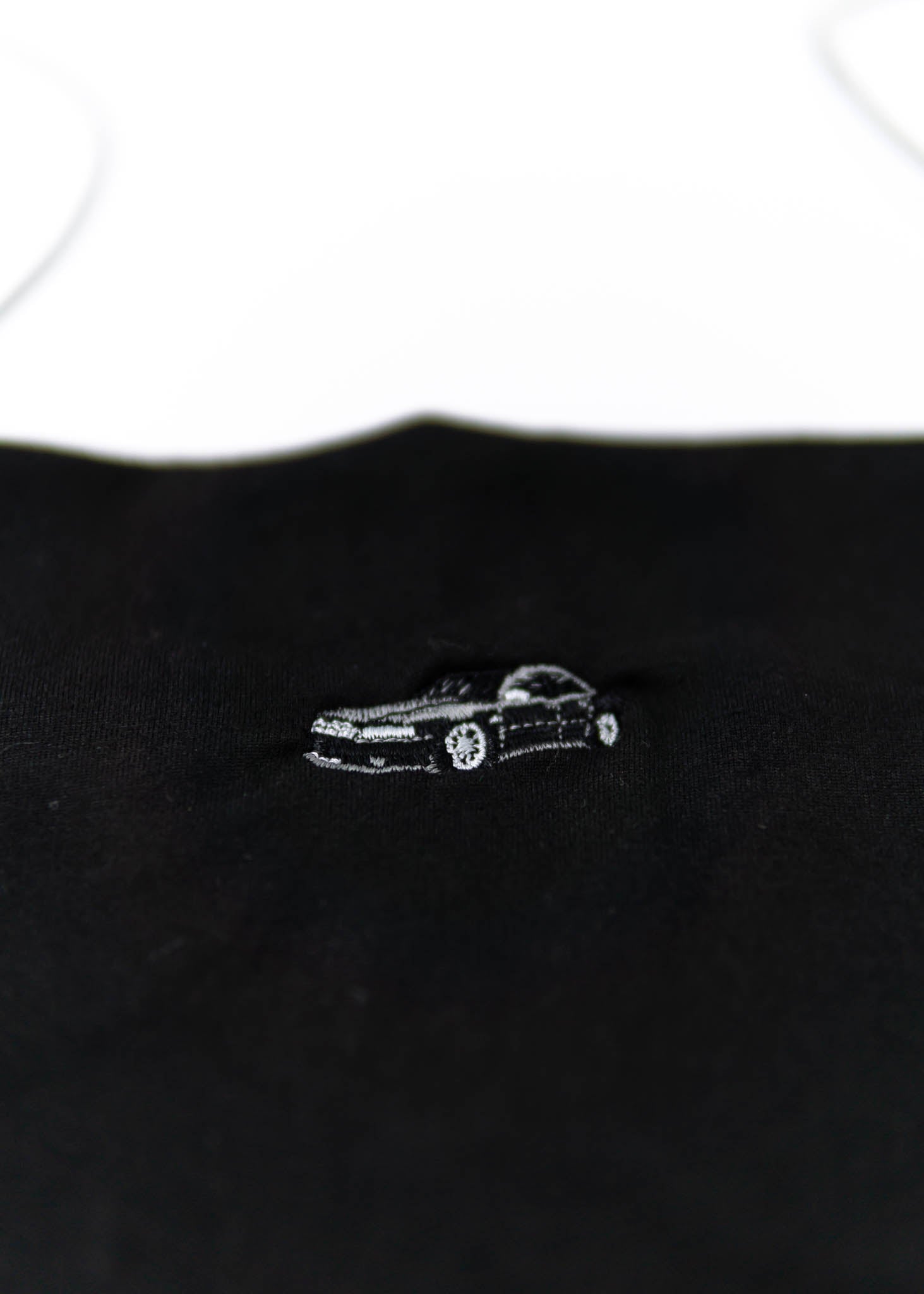 A black Audi crop top for women. Photo is a close up view of the shirt with an embroidered Black Audi D2 S8. Fabric composition is 100% polyester. The material is very soft, comfortable, non-transparent. The style of this shirt is sleeveless, spaghetti straps, with a straight neckline.