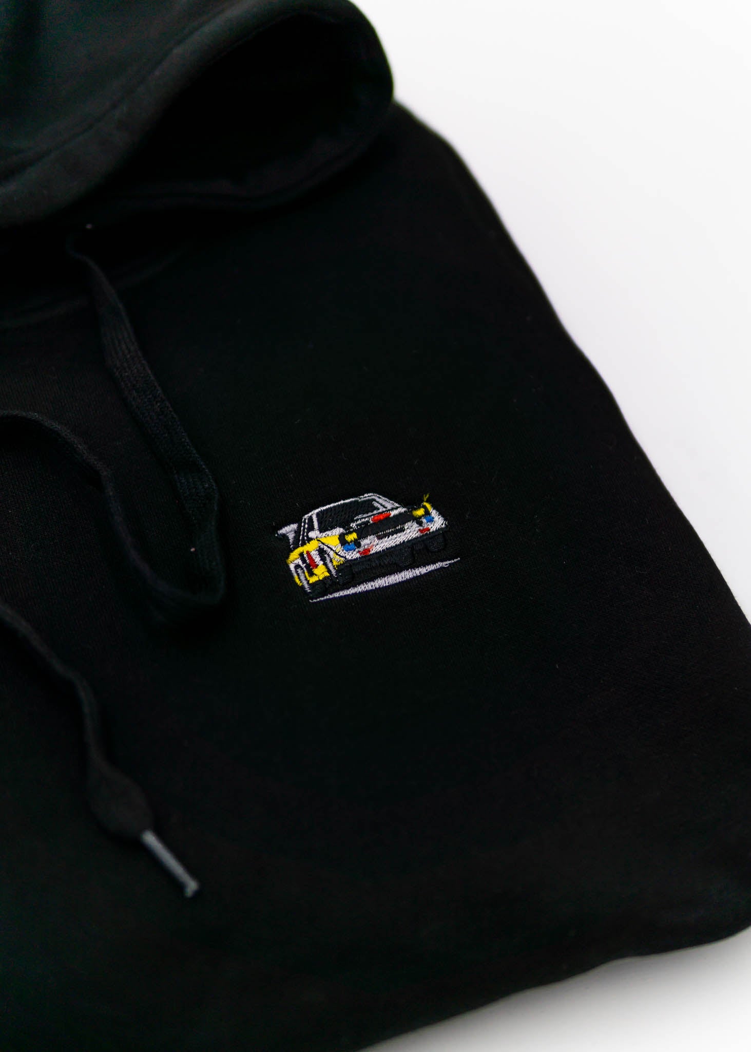 A black Audi hoodie for men and women. Photo is a close up view of the sweater with an embroidered Audi Sport Quattro S1 E2. Fabric composition is cotton, polyester, and rayon. The material is very soft, stretchy, anti-shrink, and non-transparent. The style of this hoodie is long sleeve, crewneck with a hood, hooded, with embroidery on the left chest.