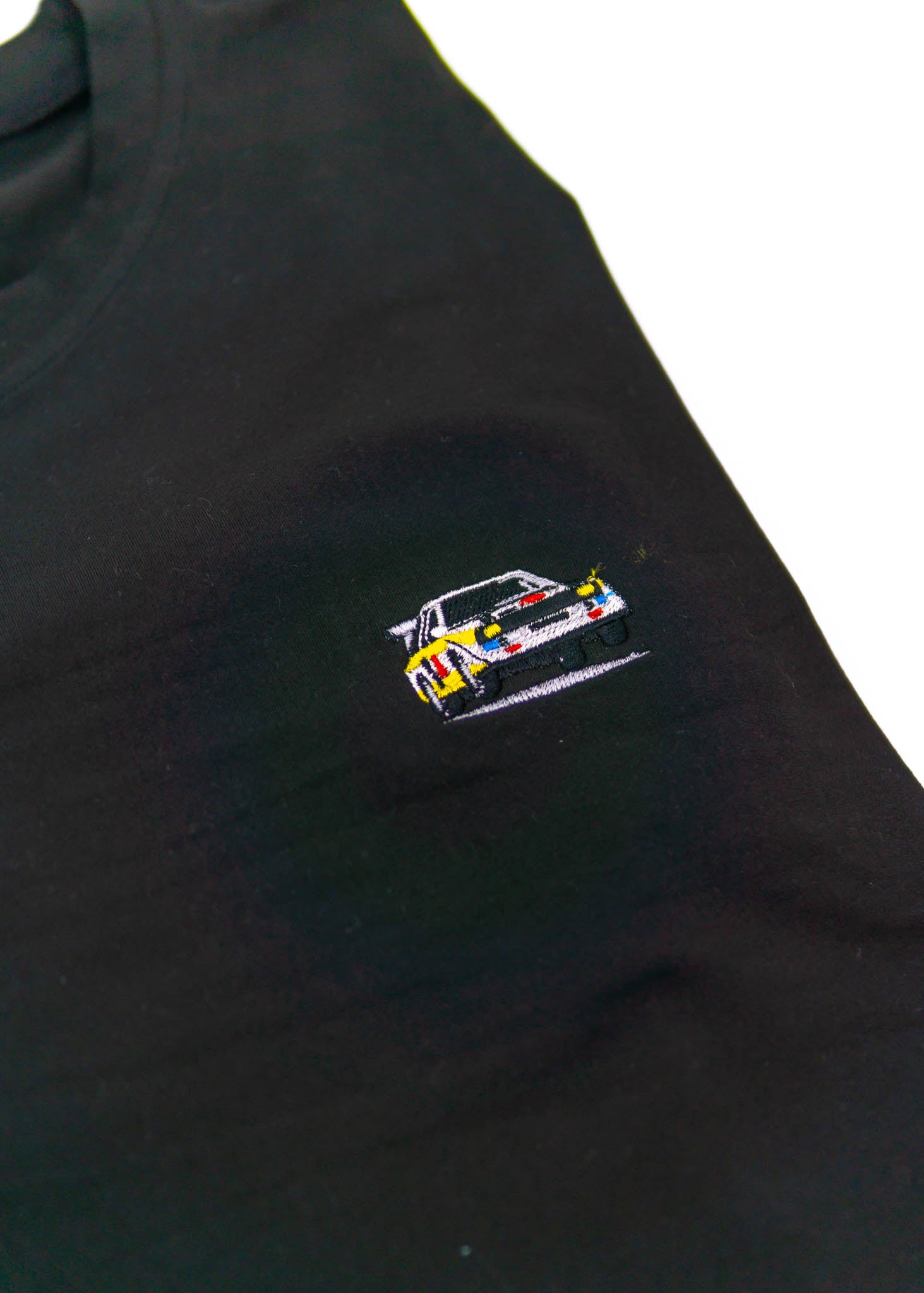 A black Audi t-shirt for men. Photo is a close up view of the shirt with an embroidered Group B Audi Sport Quattro S1. Fabric composition is a polyester, and cotton mix. The material is very soft, stretchy, non-transparent. The style of this shirt is short sleeve, with a crewneck neckline.