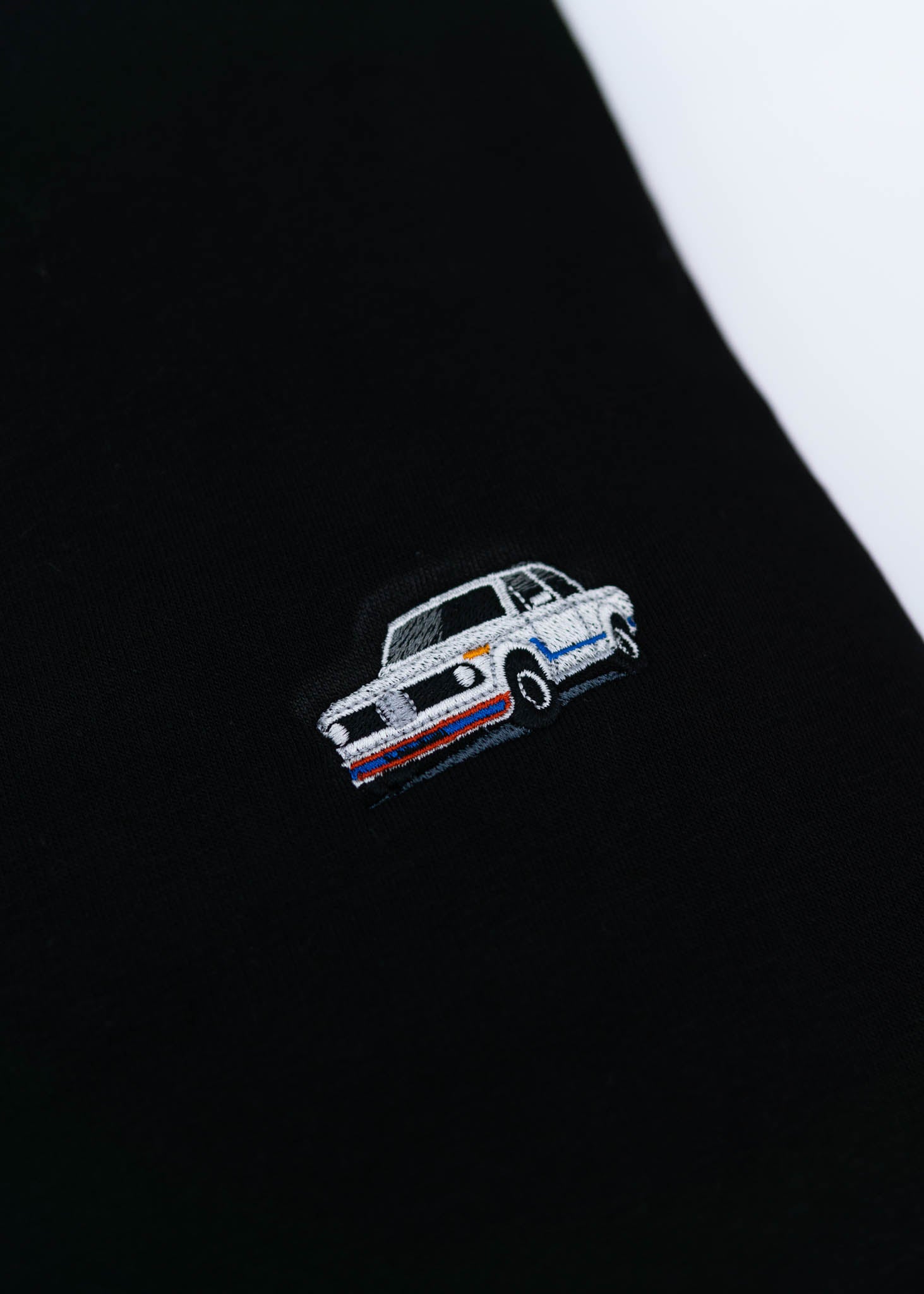 A black BMW crewneck sweater for men. Photo is a close up of the sweater with an embroidered BMW 2002 Turbo. Fabric is composed of high quality 80% cotton, and 20% polyester and fits to size. The style is long sleeve, crew neck, and embroidery on left chest.