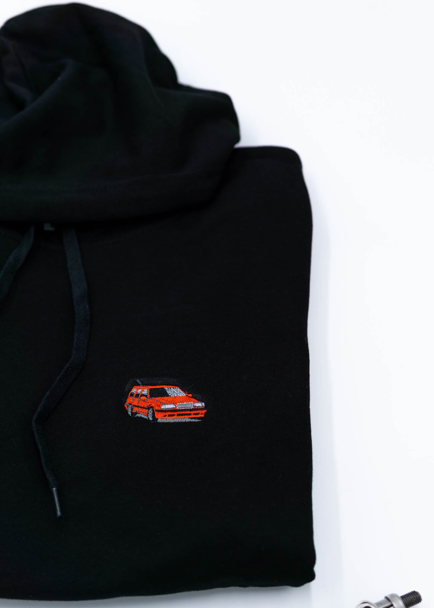 A black Volvo unisex hoodie for men and women. Photo is a close up view of the sweater with an embroidered Volvo 850R. Fabric composition is cotton, polyester, and rayon. The material is very soft, stretchy, and non-transparent. The style of this hoodie is long sleeve, crewneck with a hood, hooded, with embroidery on the left chest.