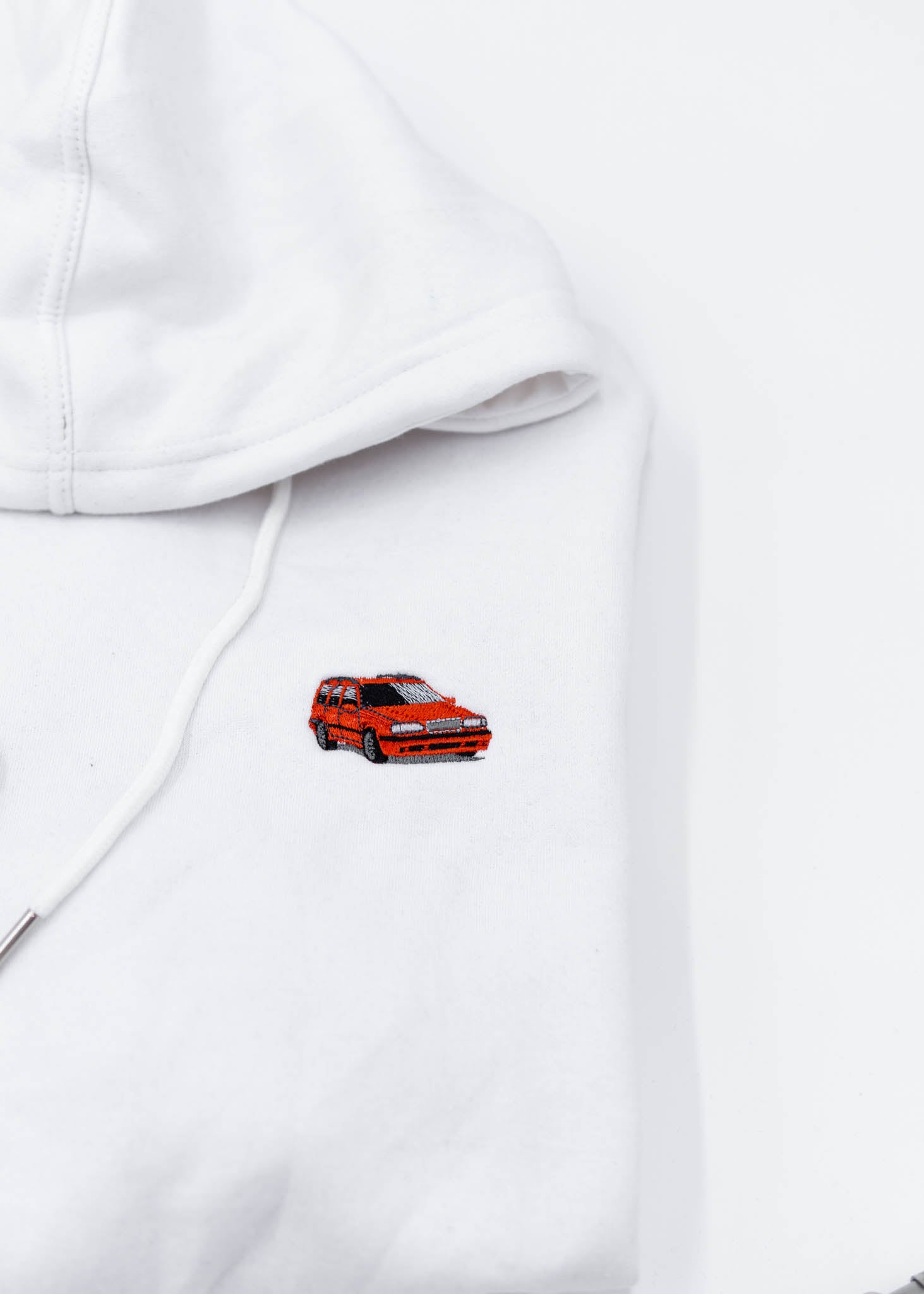 A white Volvo cropped hoodie for women. Photo is a close up view of the cropped sweater with an embroidered 850R. Fabric composition is 100% cotton. The material is soft, comfortable, breathable, and non-transparent. The style of this crop hoodie is long sleeve, crewneck with a hood, hooded, with embroidery on the chest.