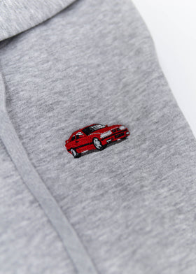 A grey E36 M3 unisex hoodie for men and women. Photo is a close up view of the sweater with an embroidered red E36 M3. Fabric composition is cotton, polyester, and rayon. The material is very soft, stretchy, and non-transparent. The style of this hoodie is long sleeve, crewneck with a hood, hooded, with embroidery on the left chest.
