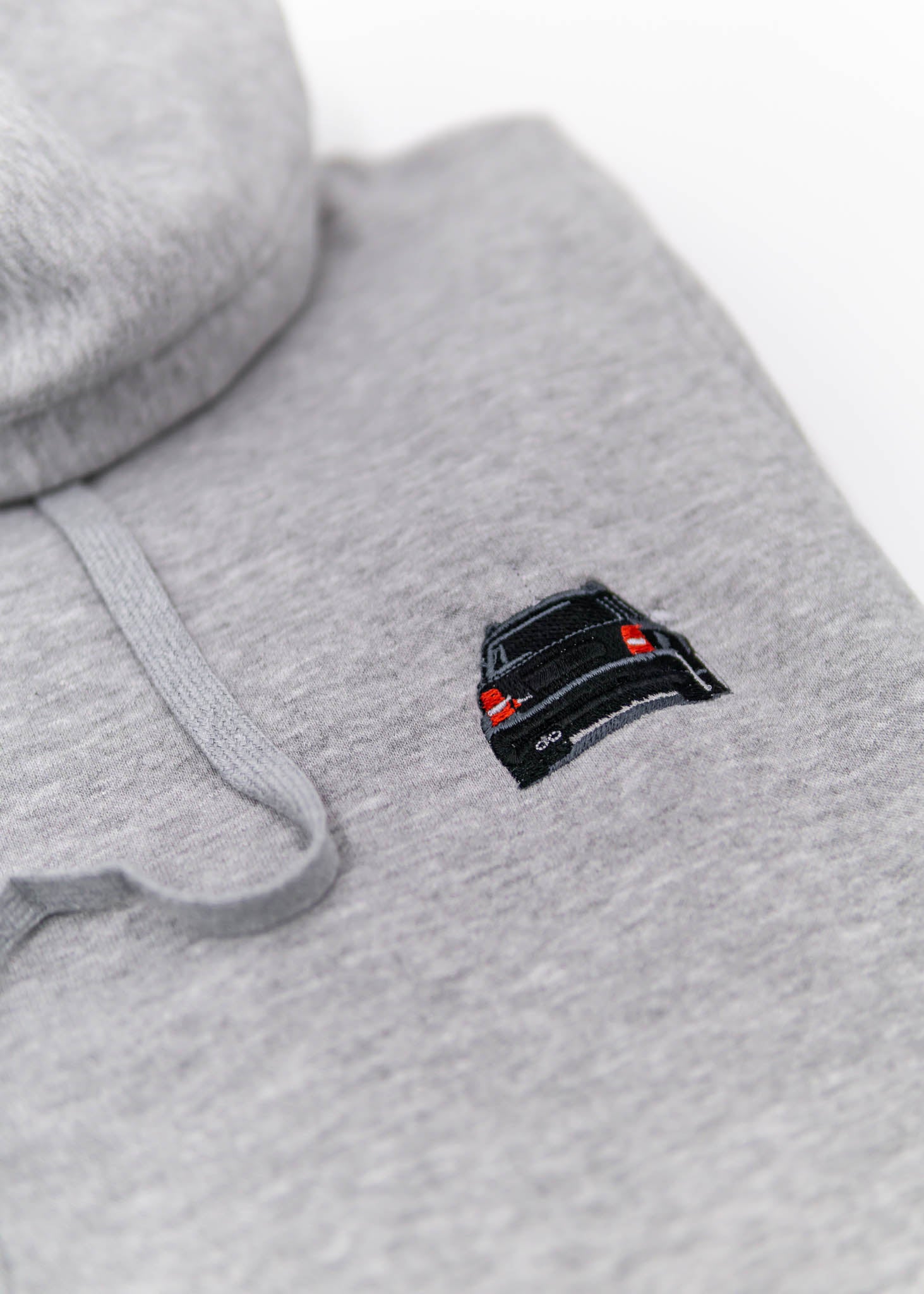 A grey Audi hoodie for men and women. Photo is a close up view of the sweater with an embroidered Black Audi B5 RS4. Fabric composition is cotton, polyester, and rayon. The material is very soft, stretchy, anti-shrink, and non-transparent. The style of this hoodie is long sleeve, crewneck with a hood, hooded, with embroidery on the left chest.