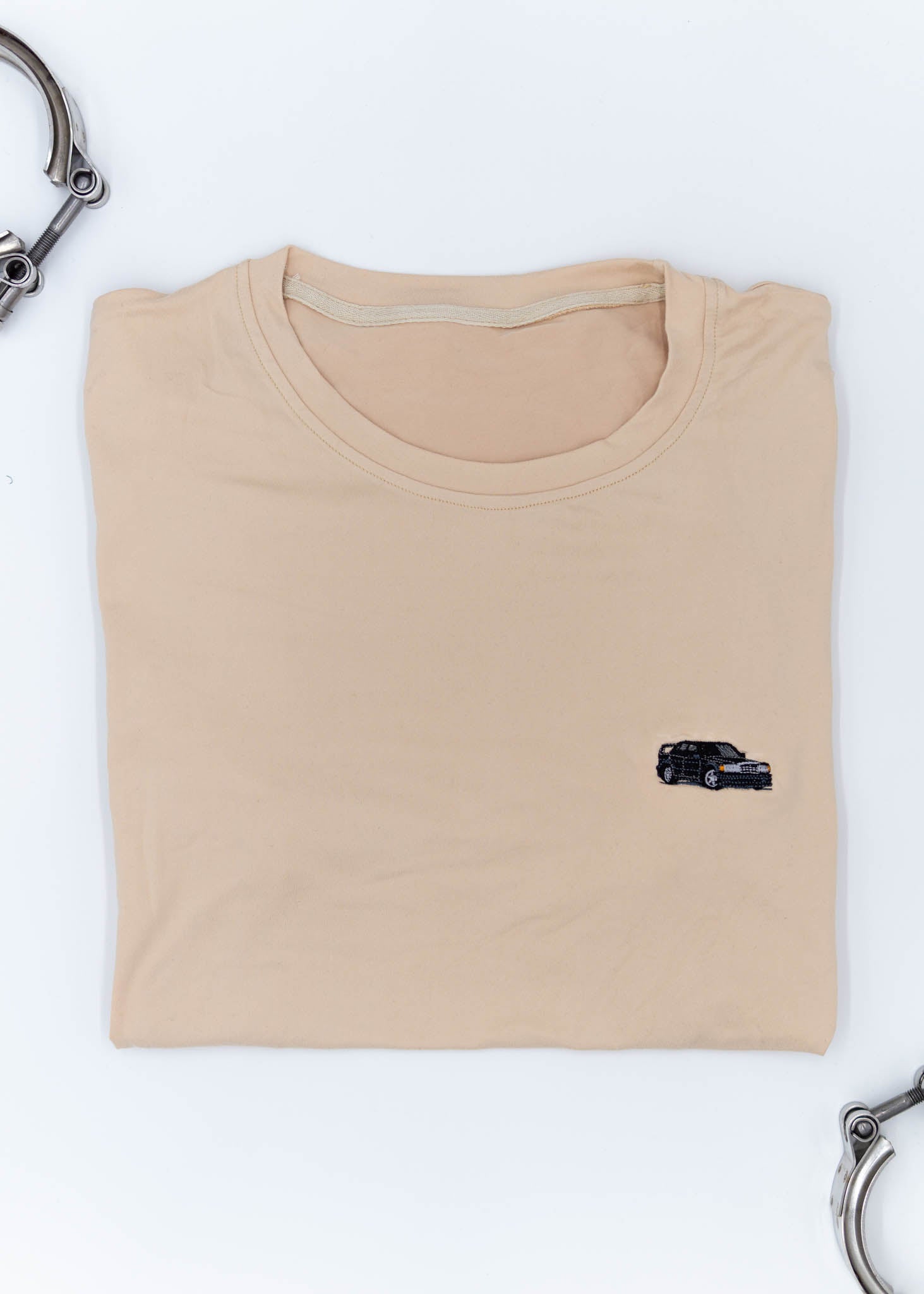 A khaki Mercedes-Benz t-shirt for men. Photo is a close up view of the shirt with an embroidered black W201 190E 2.5-16 Evo II. Fabric composition is a polyester, and cotton mix. The material is very soft, stretchy, non-transparent. The style of this shirt is short sleeve, with a crewneck neckline.