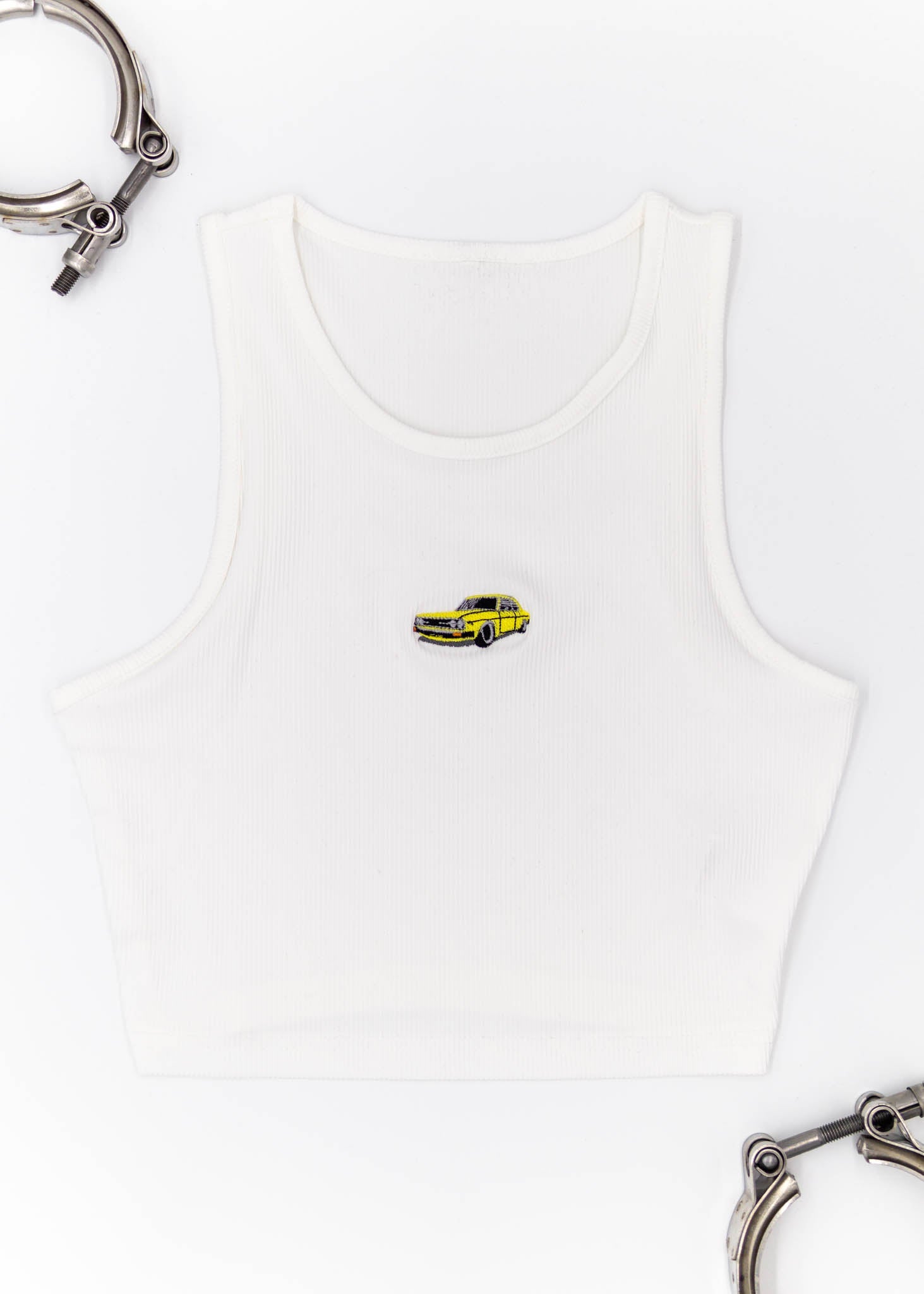    WhiteAudi100LSCropTop-Front  1463 × 2048px  A white Audi crop top for women. Photo is the front view of the top with an embroidered yellow Audi 100LS. Fabric composition is polyester, and elastine. The material is stretchy, ribbed, and non-transparent. The style of this shirt is sleeveless, with a round neckline.